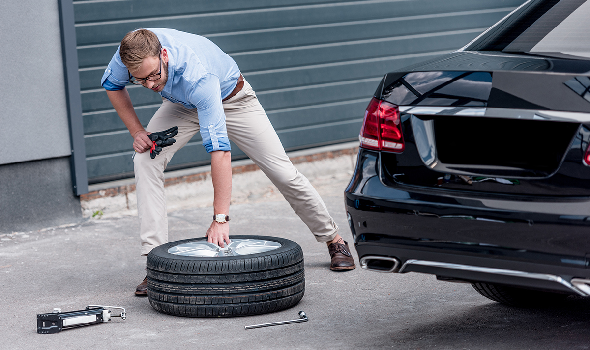Someone getting their spare tyre from their car