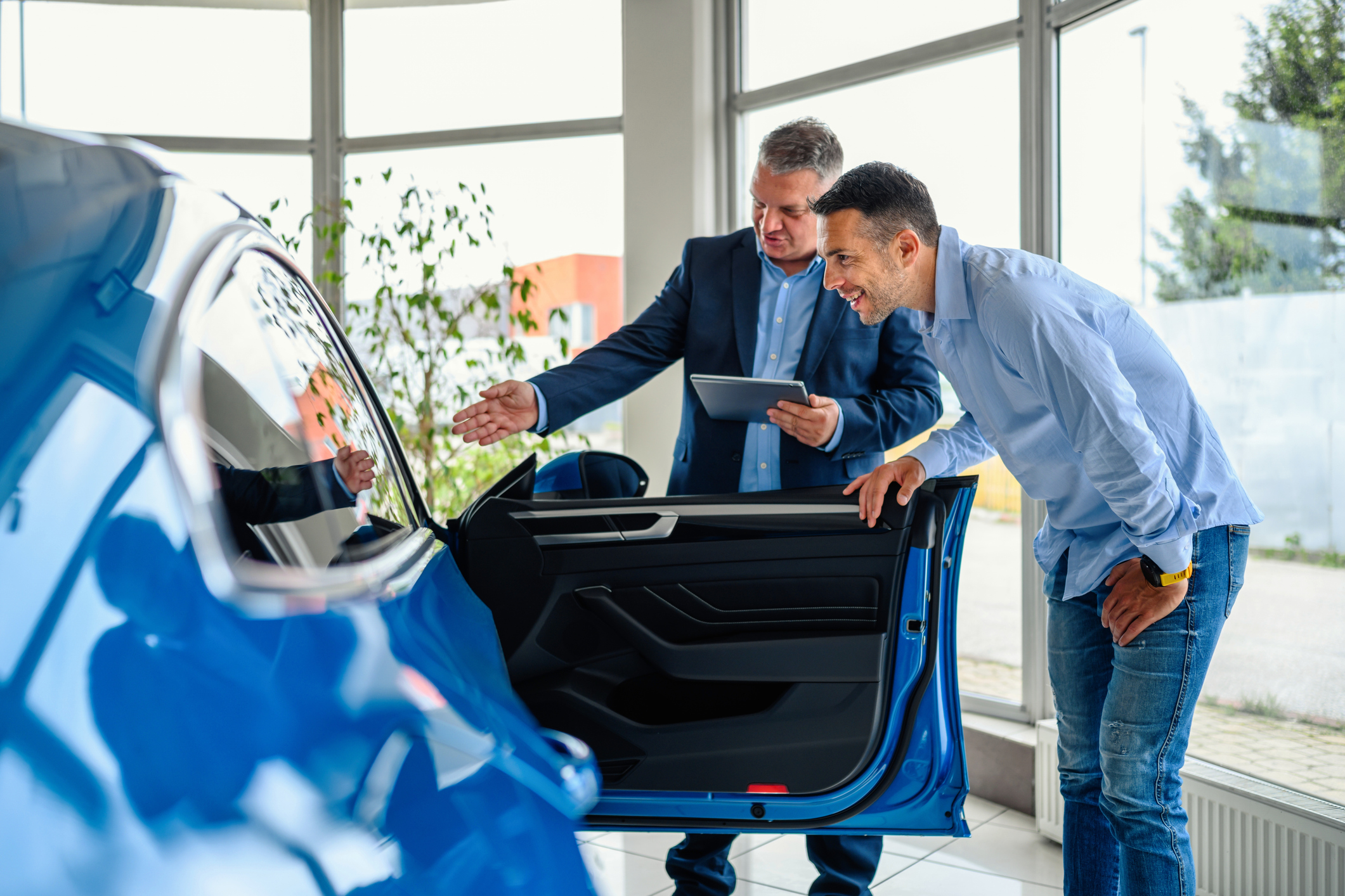 Salesman helping the male customer to choose a new car.  