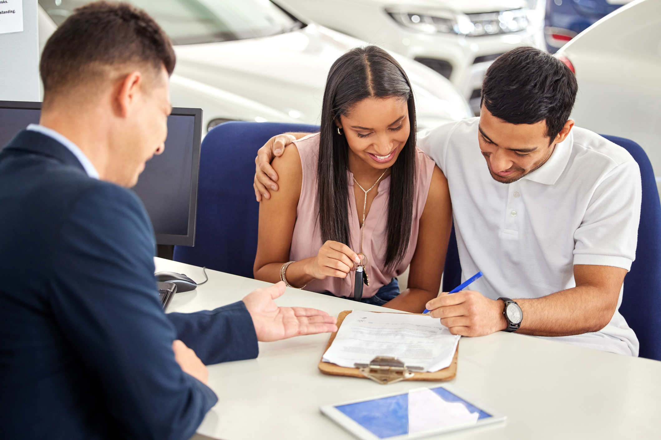 A young couple in a car dealership signing their car lease  