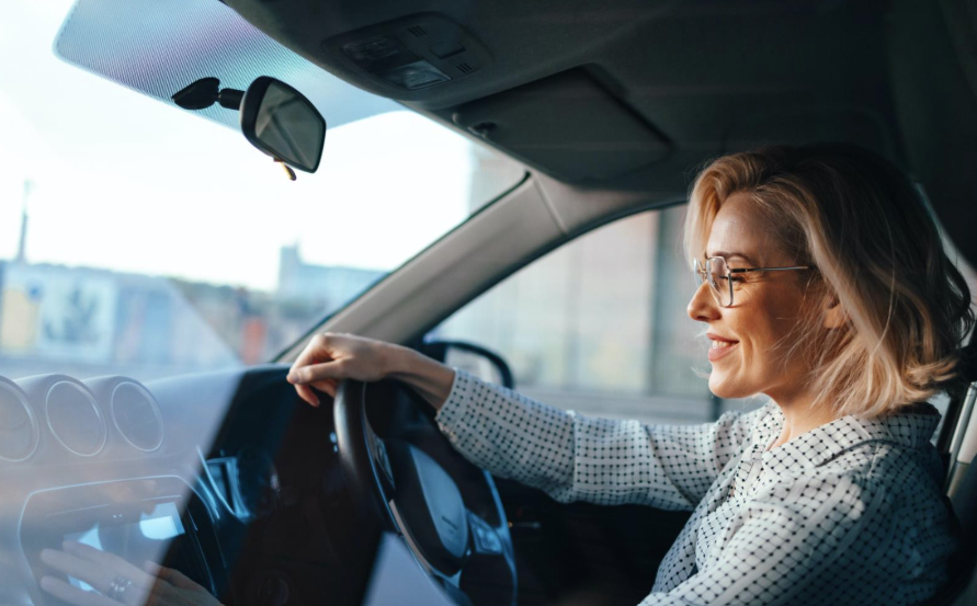 Happy business woman listening to music while traveling with her car around the city. 