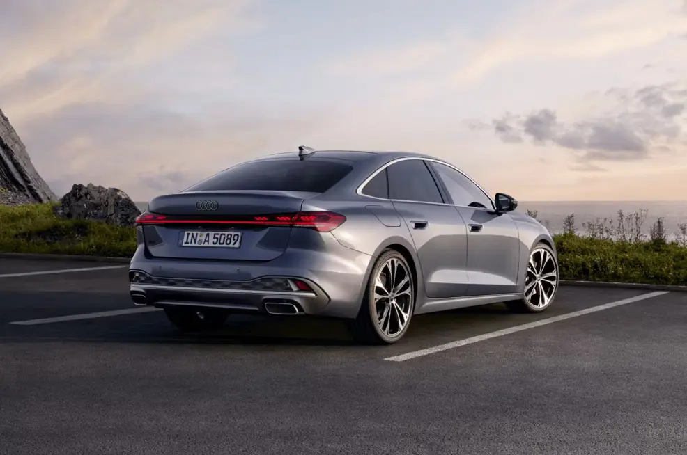 Rear view of silver Audi A5 Sportback parked with ocean and cliff background at sunset