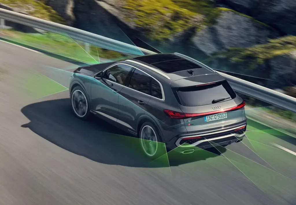 A grey Audi Q5 driving alongside a mountainous road