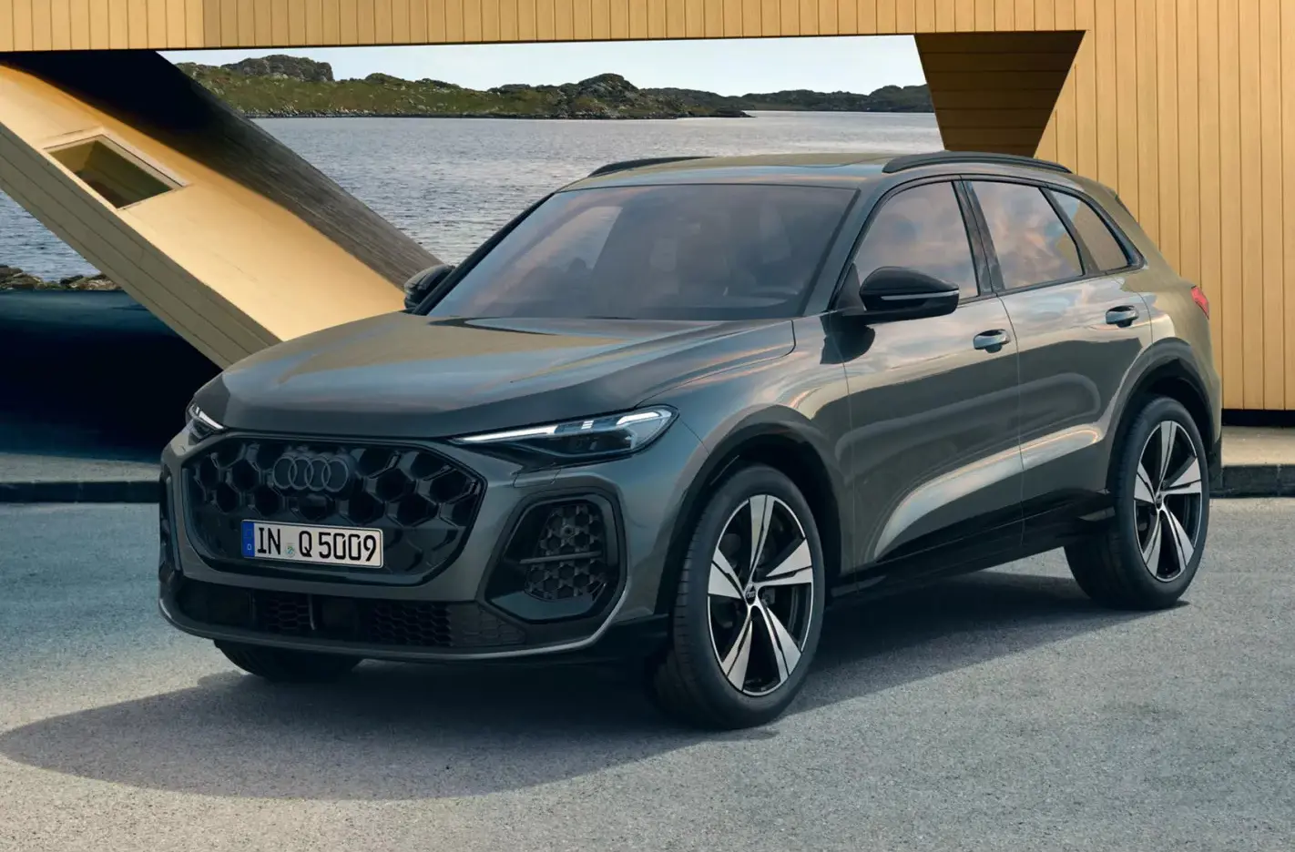 Rear front view of a green Audi Q5 parked with ocean and hilly background