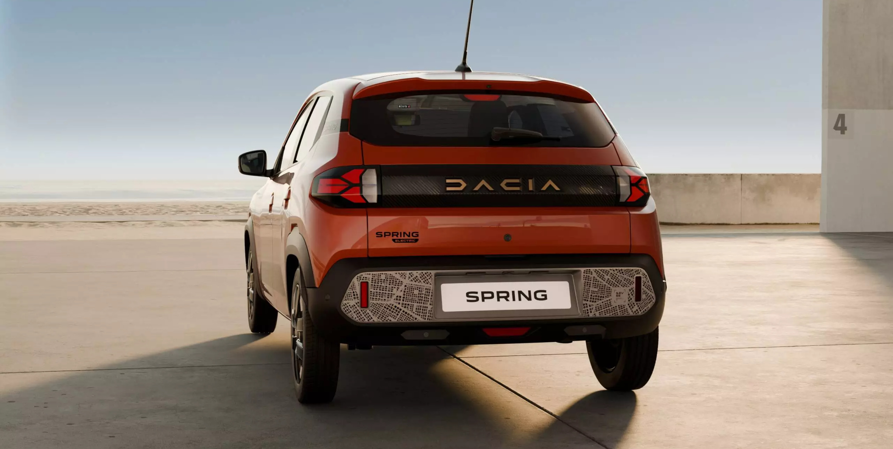 An orange Dacia Spring EV car parked in a bright open car park