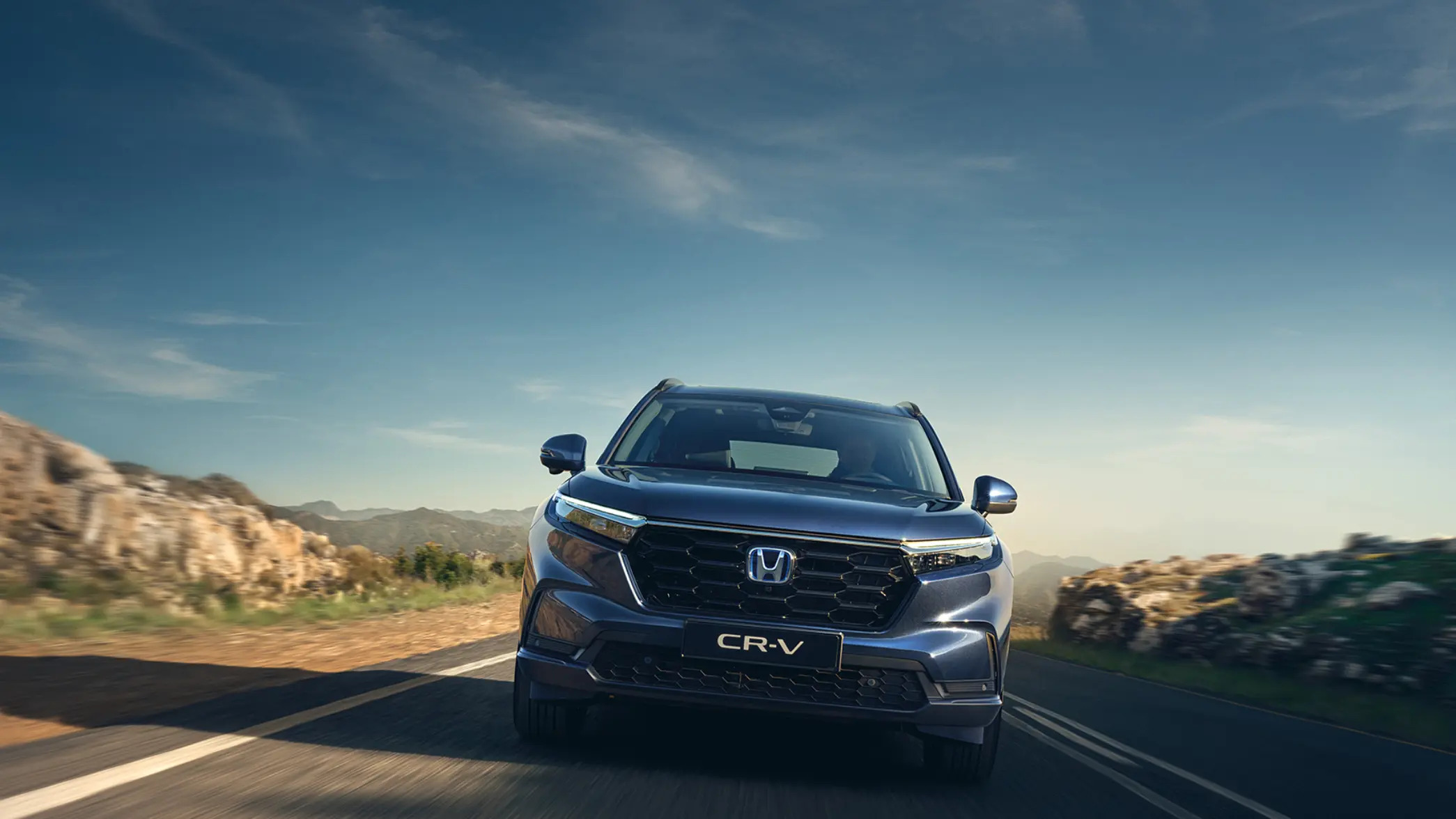 An individual driving on a straight road through the mountains in a blue Honda Civic car