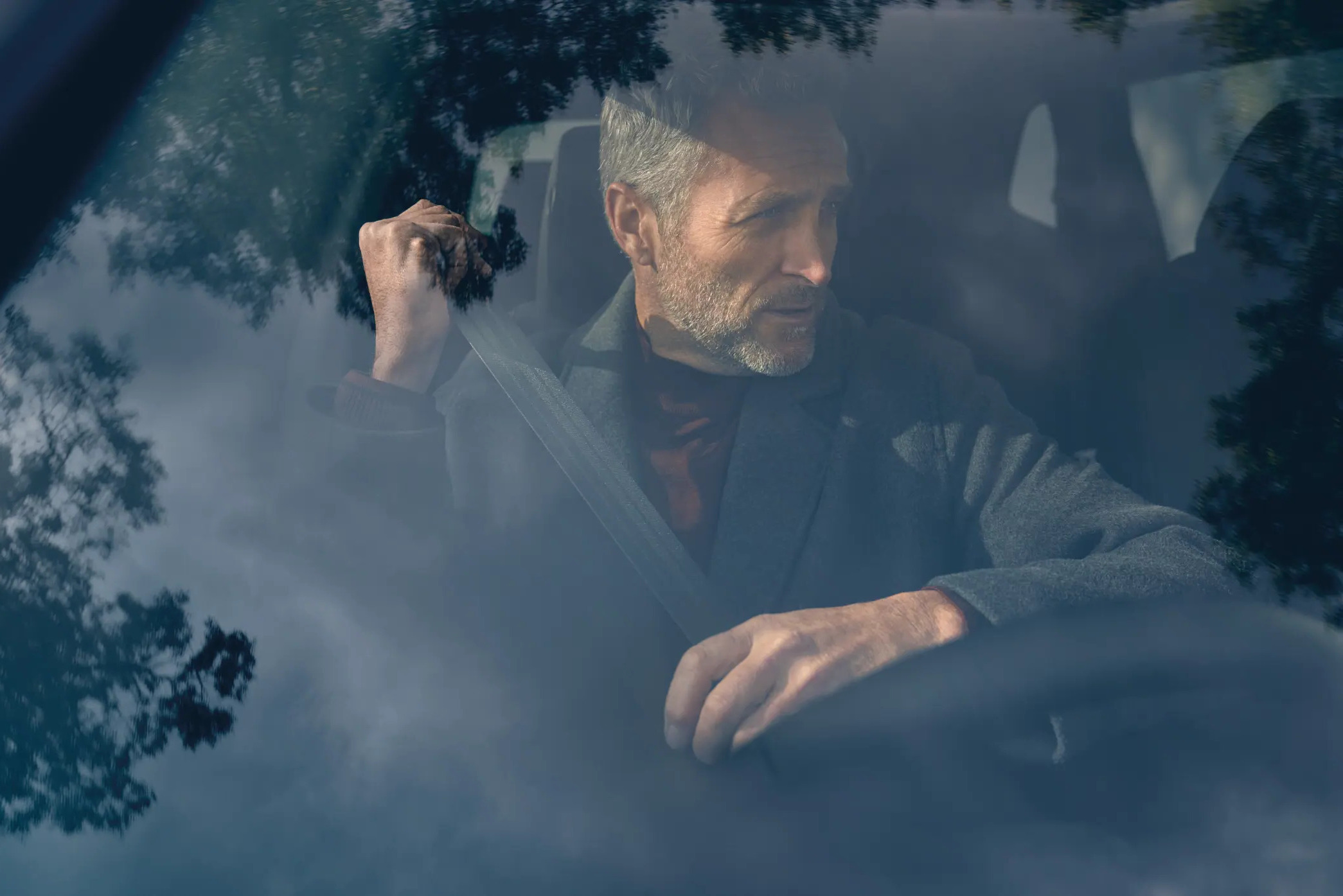 A close-up shot of a smartly dressed man putting his belt on in a Honda CR-V car