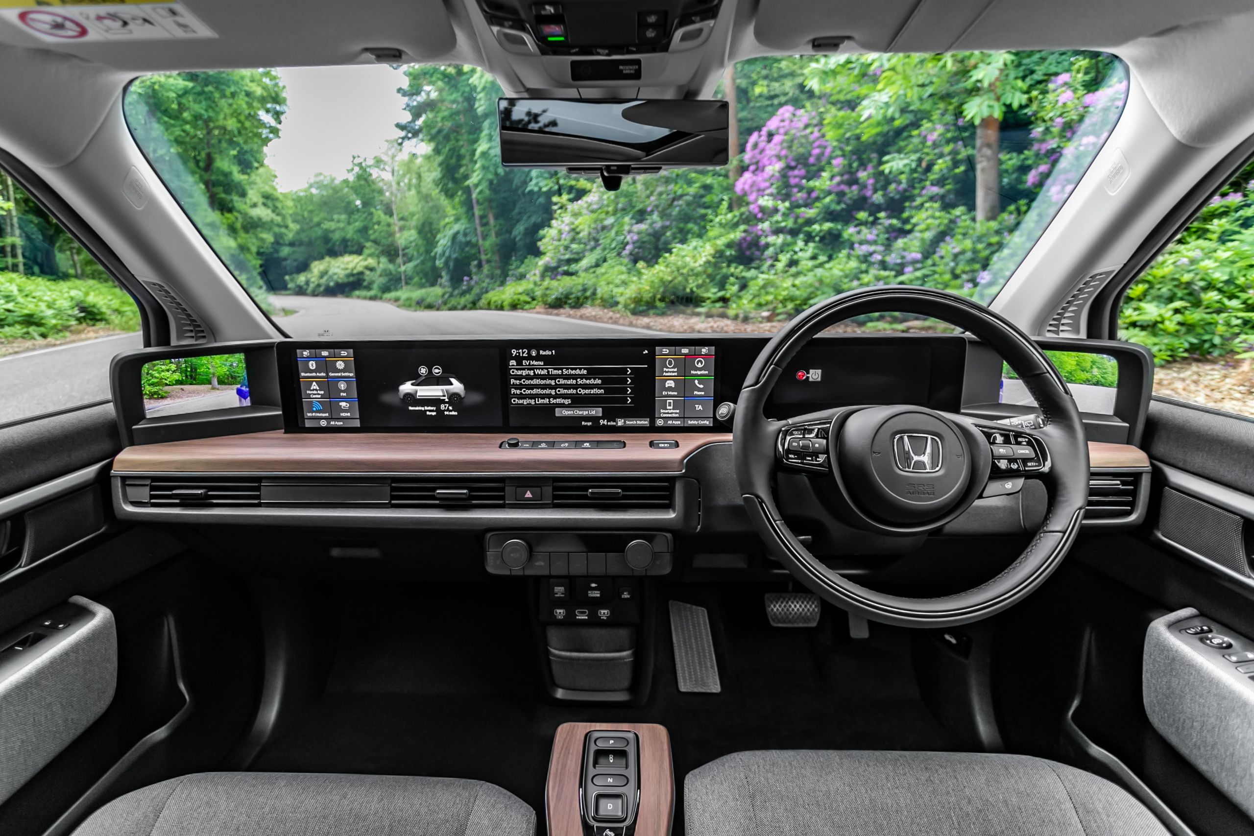 The interior of the driver and passenger seats with the dashboard, navigation system, and view of the countryside through the windscreen