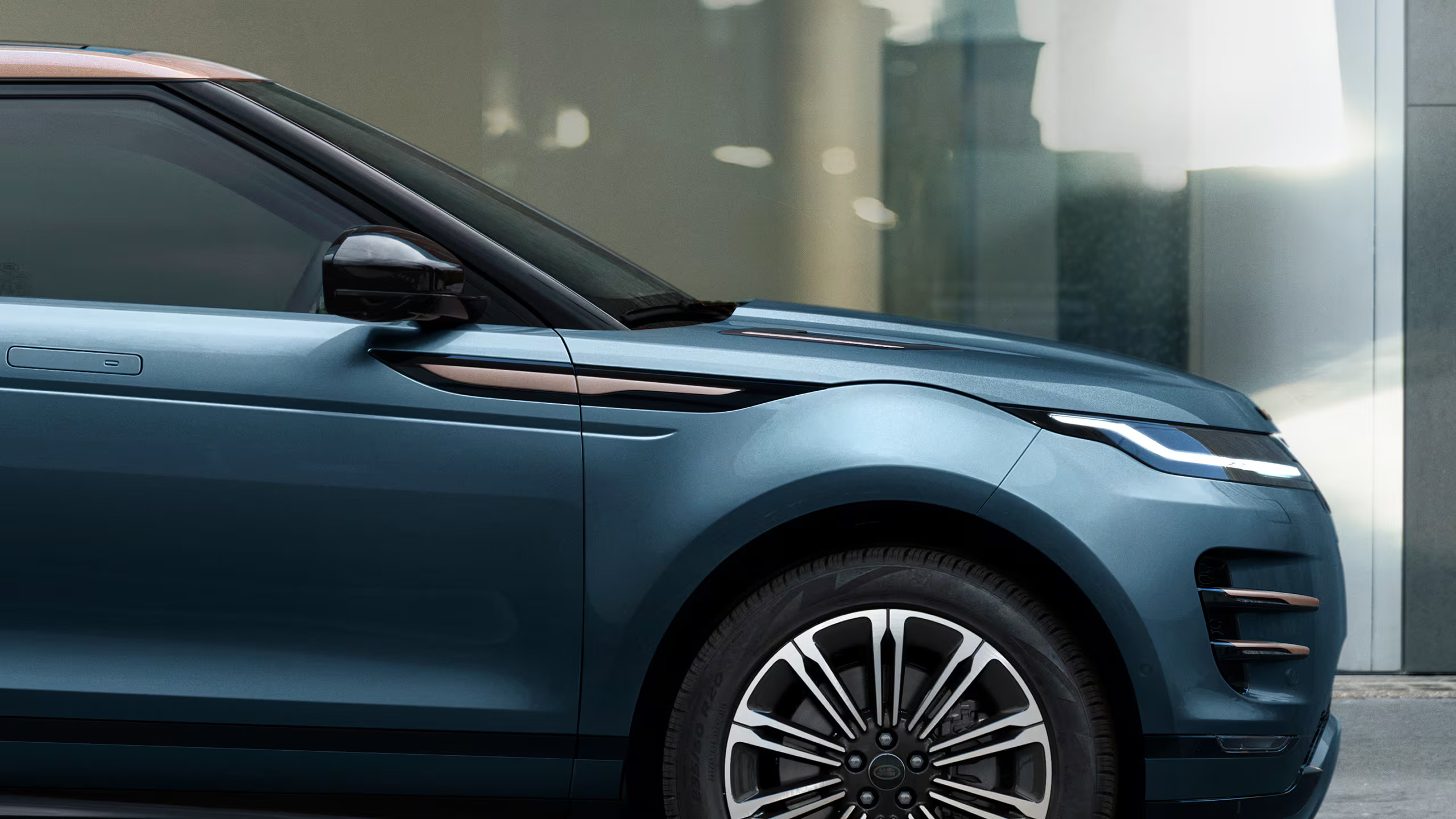 Focused image of the front half of a blue / grey and brown Range Rover Evoque car