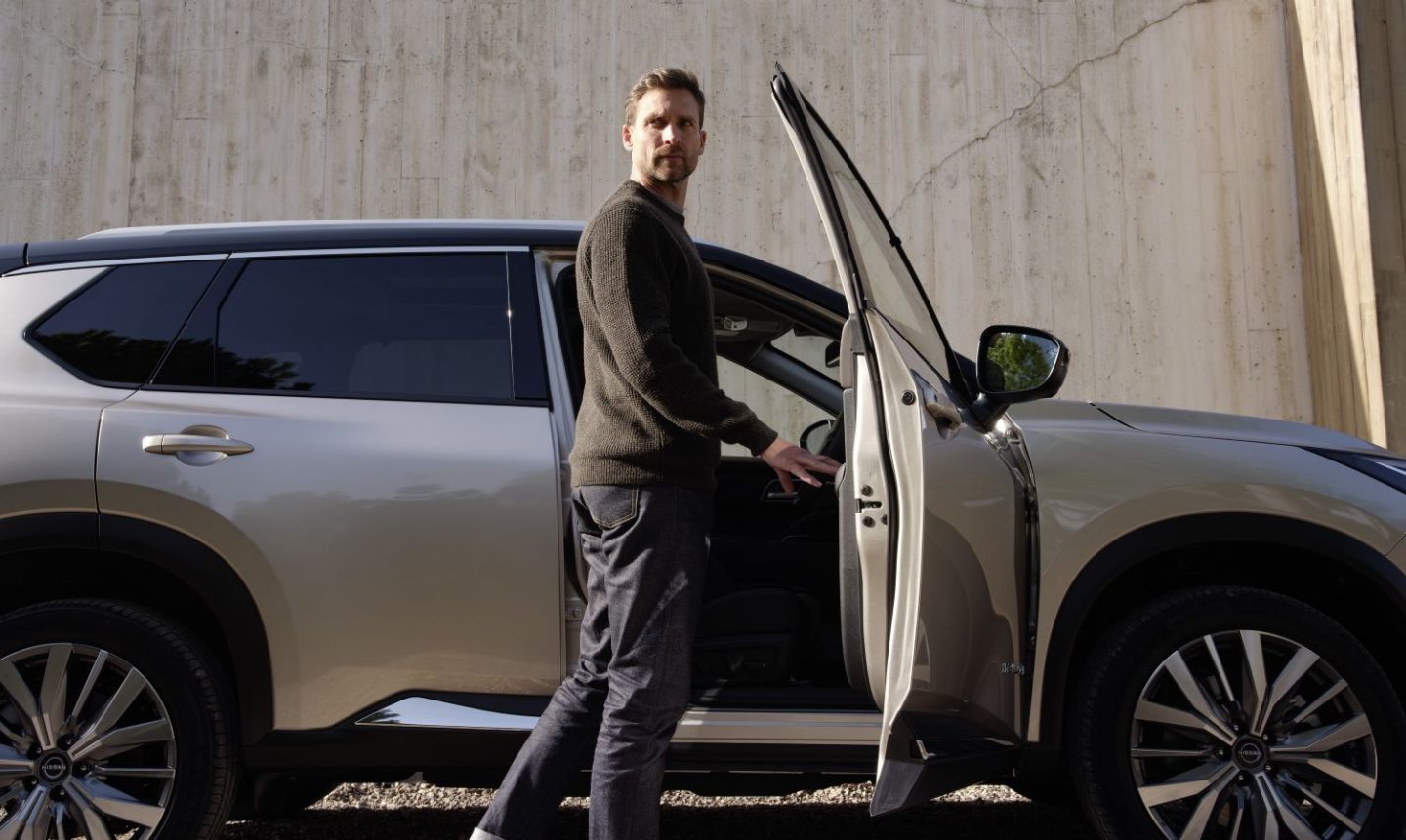 A white male ready to get into the driving seat of a gold Nissan X-Trail car