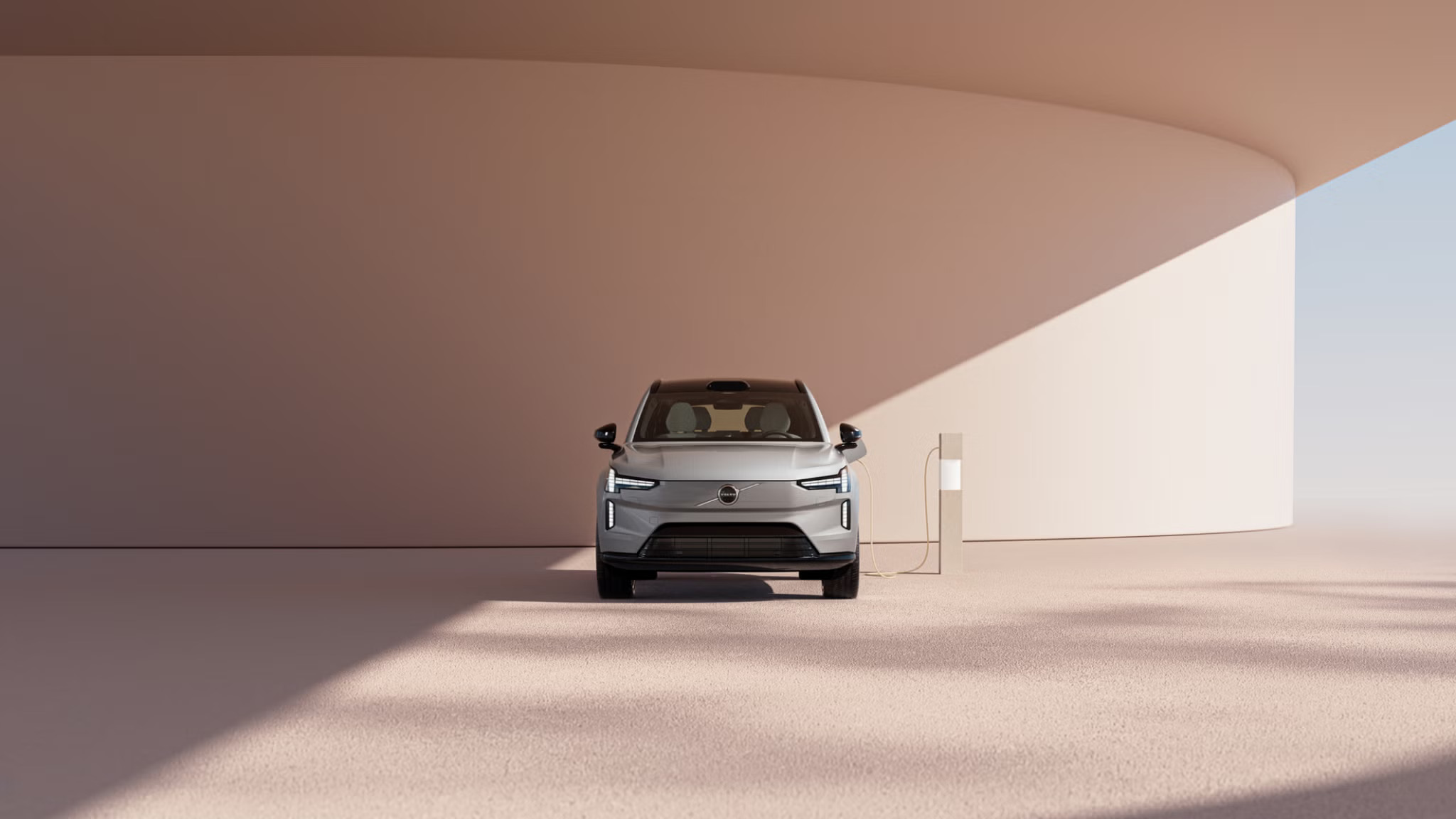 the front of a grey Volvo EX90 electric car plugged into an electric vehicle charger