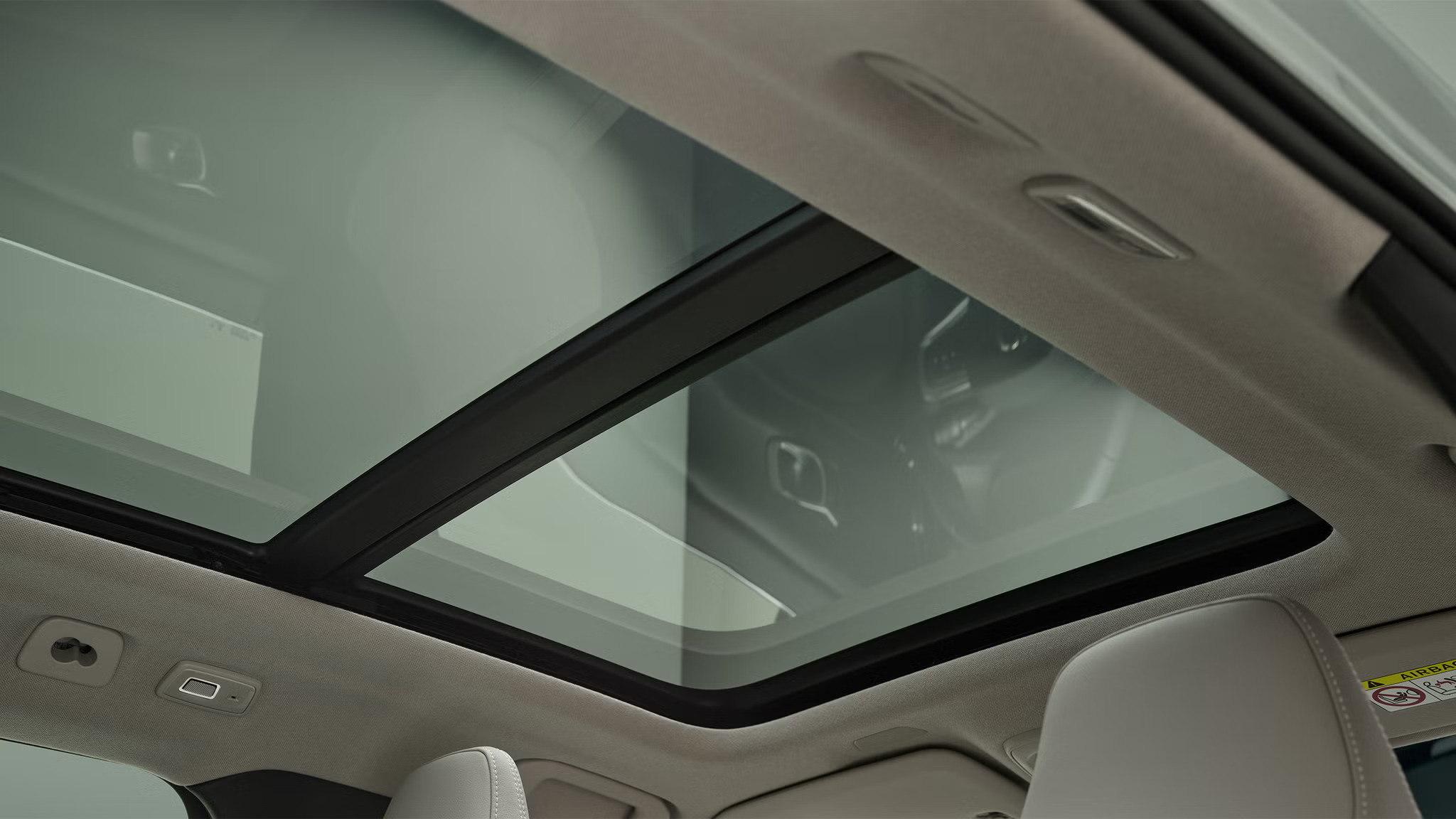 Looking through the panoramic roof of a car with cream interior
