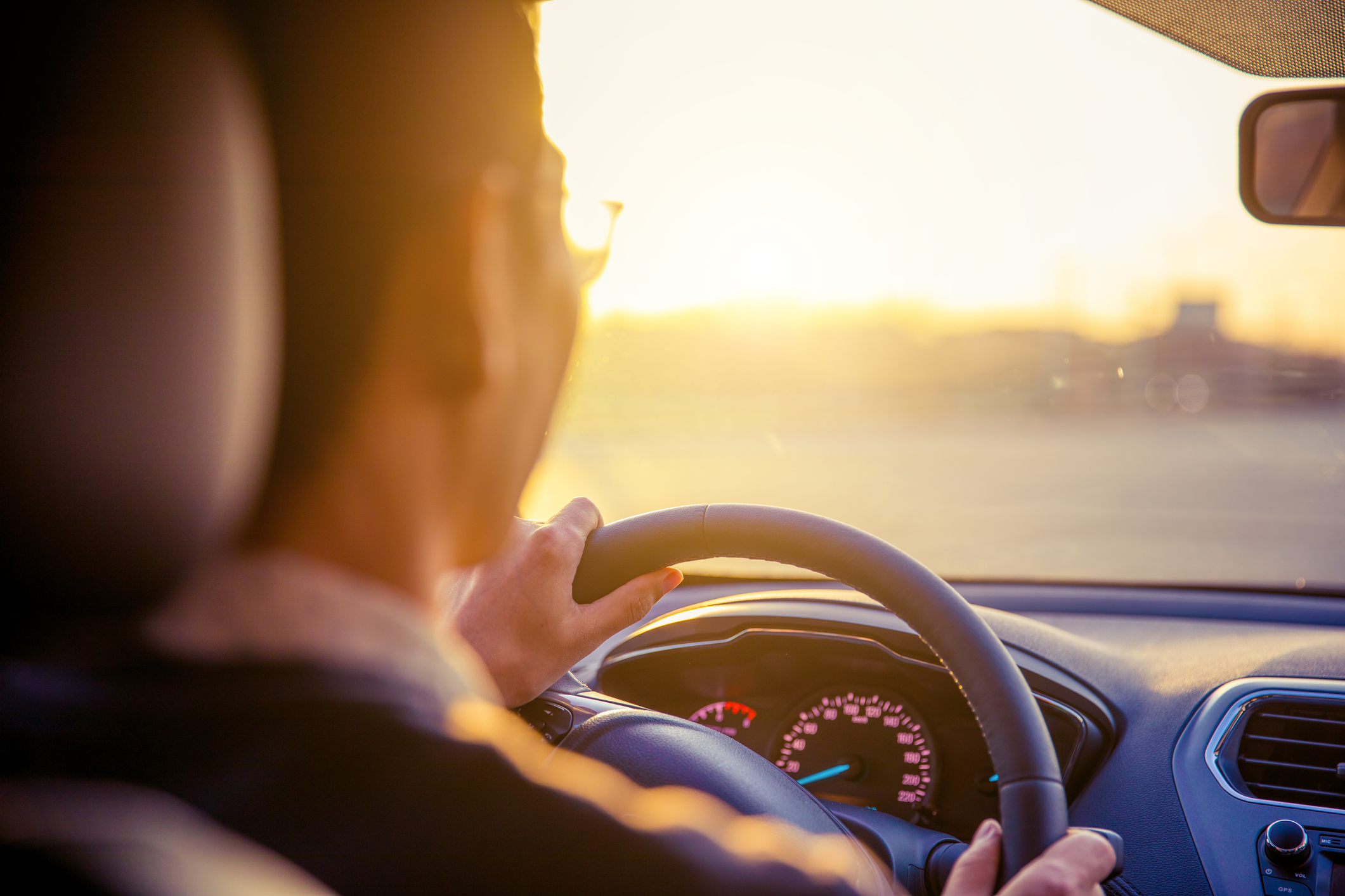 A man driving his car into the sunset